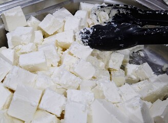 White cheese feta cubes in the store market. Group pieces of milk cheese background. Healthy lifestyle ingredient.
