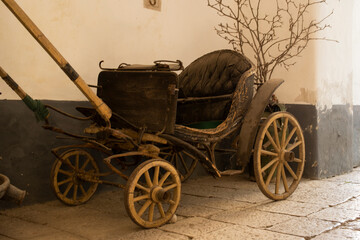 Fototapeta na wymiar Antique carriage with wooden wheels and wicker (wood) carriage and iron front crossbows.