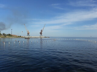 Fototapeta na wymiar Construction works. Two cranes by the sea.