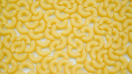 Curly pasta closeup white background. Tasty dry uncooked ingredient for traditional Italian cuisine. Top view.