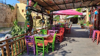Fototapeta na wymiar Greek restaurant without people. Colorful chairs and tables outside.