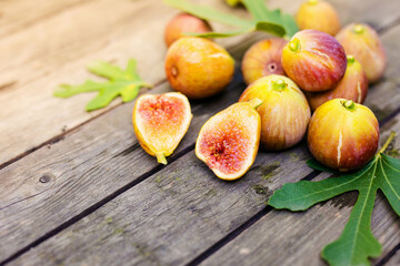 Fresh fig sliced in half with whole figs in the background, on a wooden surface. Fig fruits on a wooden platter.