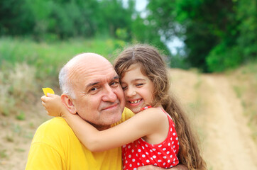 Portrait of granddad and granddaughter smiling at the park