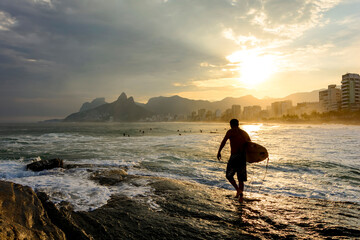 Surfer at sunset in Arpoador beach at Ipanema in Rio de Janeiro