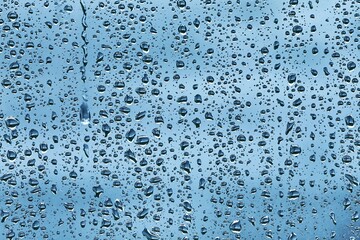 Raindrops on window with dim outdoor background rainy day