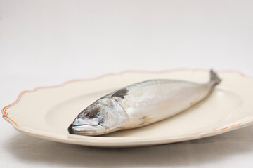 Old decorative presentationdish with tasty raw mackerel fish on table with an embroidered tablecloth