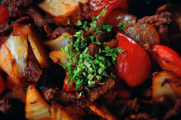 Fried food. Cooked meat with vegetables and salad. Close up. Lamb or beef with sweet peppers, onions and herbs. Seasonings and spices. Dish from the menu of cafe or restaurant of Oriental cuisine.