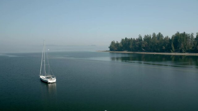Sailboat Floating At The Calm Waters Of Mayo Cove Near Penrose Point State Park At Early Morning In Lakebay, Washington, USA. - aerial drone shot
