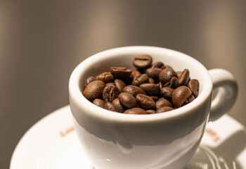 Cup with roasted coffee beans on white background. Copy space 
