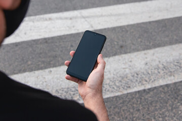 Pedestrian looking at his mobile while crossing the road