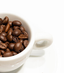 Cup with roasted coffee beans on white background. Copy space 