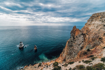 Autumn sea landscape with overcast sky and volcanic rocky coastline. Calm sea on a background of...