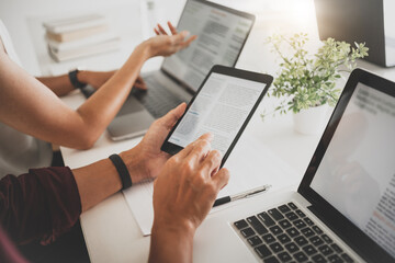 College / University students sitting at library doing assignment together.
