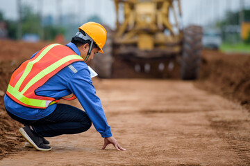 Asian engineers watch road rebuilding and inspect the construction of the road at the construction site.