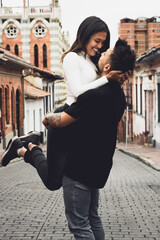 pareja de jovenes en el centro de bogotá en una calle  alzando a la mujer en sus brazos