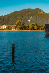 Beautiful alpine sunrise view with the moon and a hot air balloon in the background at the famous Tegernsee, Bavaria, Germany