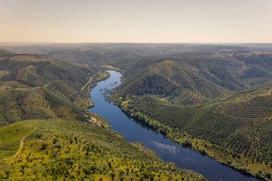 Aerial view of the Tagus river flowing in between the forst hills, Belver, Portugal.