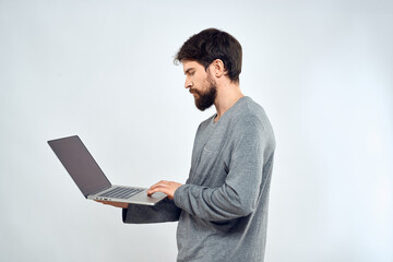 A man in a gray sweater with a laptop hands lifestyle technology communication internet work