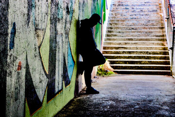 Silhouette man standing against graffiti in the shadows