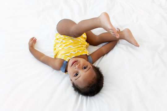 Cute toddler rolling upside down on bed