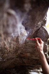 Preparing rock surface for bouldering, cleaning holds with a brush