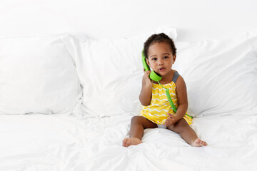 Cute toddler girl holding a green corded phone