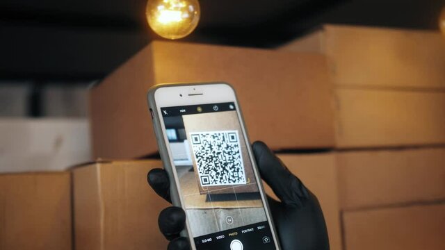 Asian man checking qr code by mobile phone on warehouse, big stock e-commerce storage, courier checking good for delivery service