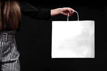 Woman's hand holding shopping bag black background