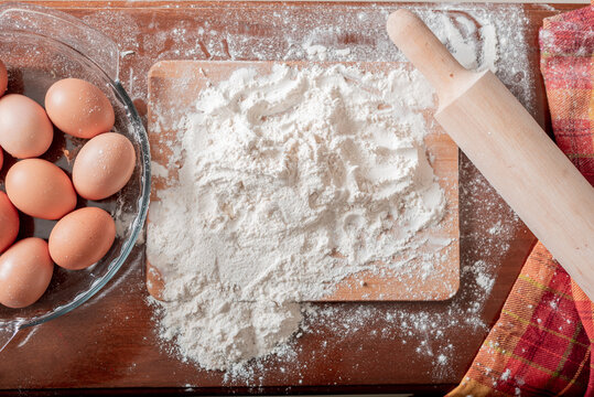 Ingredientes torta casera con huevos y harina regada sobre tabla con un molinillo