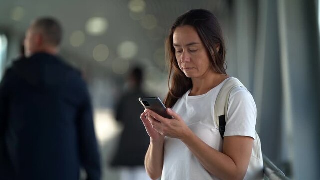woman is using smartphone in subway underpass, checking social nets and surfing internet