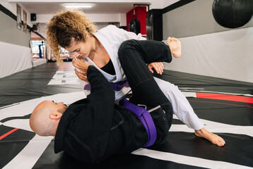 two female and male martial arts fighters practicing new techniques on a gym mat