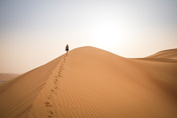 figure walking up a sand dune in Rub al Khali Desert at the Empty Quarter, in Abu Dhabi, UAE © katiekk2