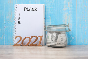 2021 New Year with money glass jar and wooden number. financial, Resolution, Goals, Plan and saving Concept