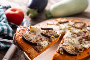 Autumn pumpkin pizza with vegetables on wooden table.	