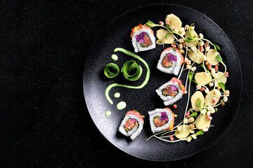 Sushi rolls set served on black plate on dark background.Design concept.Top view