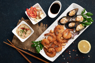 Shrimp and seashells  traditional dish on dark background top view. Shrimp fried in garlic batter with lemon and parsley. Healthy food. Clean eating.