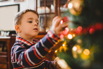 Little boy decorating Christmas tree at home