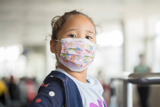 Little girl in mask sitting in the airport and airplane while covid epidemia