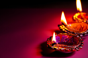 burning diya on Happy Diwali purple background for light festival of India, copy space