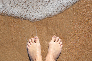 Woman bare feet on sand with sea foam