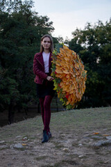 Beautiful girl in the park. Holds an umbrella covered with autumn yellow leaves. Autumn.