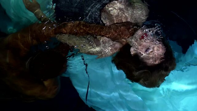 black man is pulling young beautiful woman underwater, romantic and tragedy shot