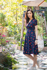 Young beautiful asian women sitting in cafe with beautiful garden and small waterfall. Happy young girl having vacation and enjoying the view. Women in cafe waiting for her order.