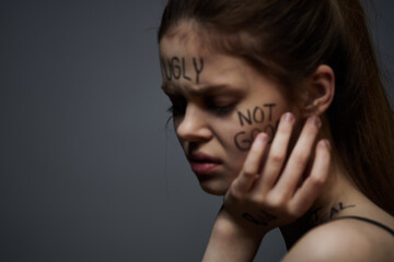Emotional woman with inscriptions on body upset with frustration gray background
