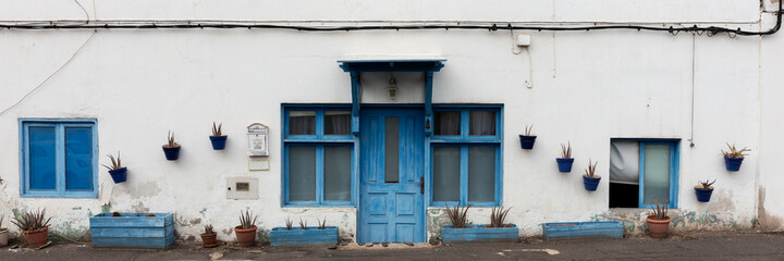 House facade with wooden blue entrance door. Panorama