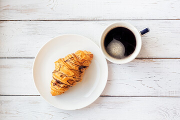 Delicious freshly baked croissant with chocolate and aroma coffee on a white wooden background on the table. Great Breakfast in the morning. Rustic style.
