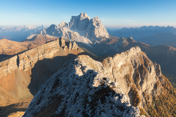 Obraz premium Seasonal autumnal scenery in highlands. Alpine landscape in Dolomite mountains, Southern Tyrol area, Italy. Popular travel destination in autumn. Aerial autumn sunrise scenery with yellow trees.