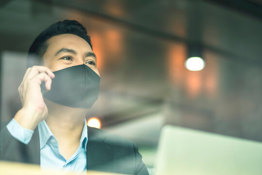 smart attractive asian male businessman wearing face mask virus protecting working with smartphone in cafe new normal working lifestyle business concept - Powered by Adobe