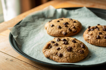 Homemade cookies on cooling tray. Cookies with chocolate on dark wooden background. Homemade Chocolate chip cookies.