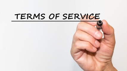 the hand writes text TERMS OF SERVICE with a marker on a white background. business concept